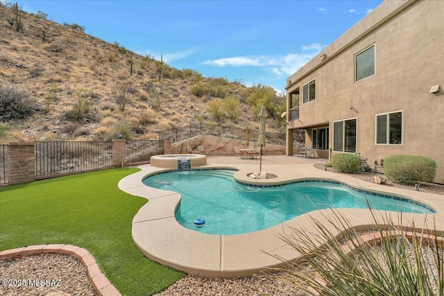 view of swimming pool with a patio area, a pool with connected hot tub, and a fenced backyard