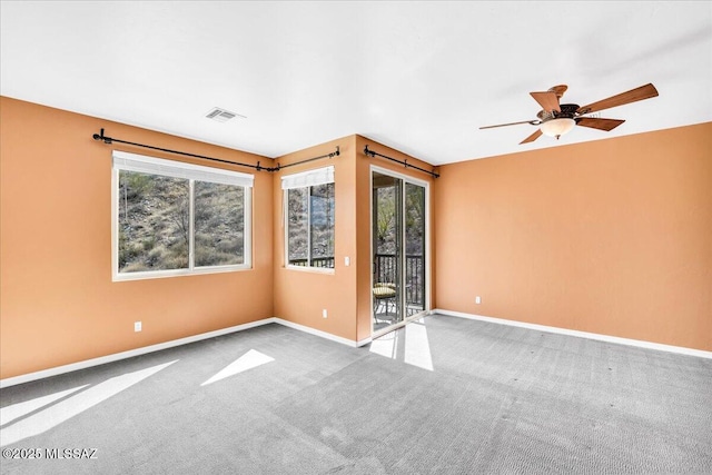 carpeted empty room with visible vents, ceiling fan, and baseboards
