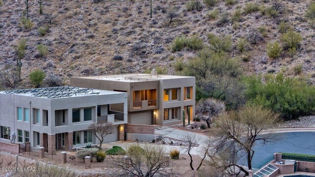 back of house featuring an attached garage, a balcony, and stucco siding