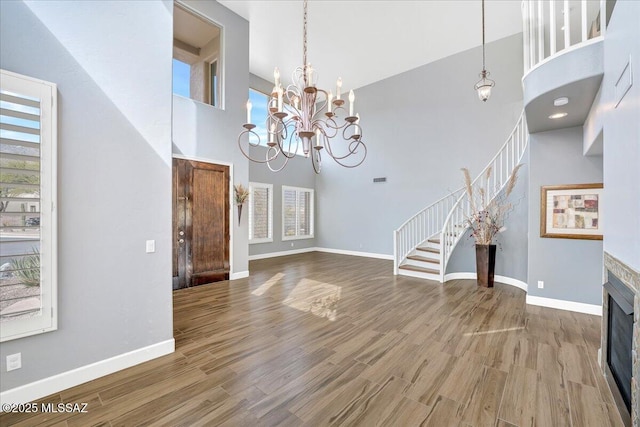 unfurnished living room with stairway, baseboards, wood finished floors, and a towering ceiling