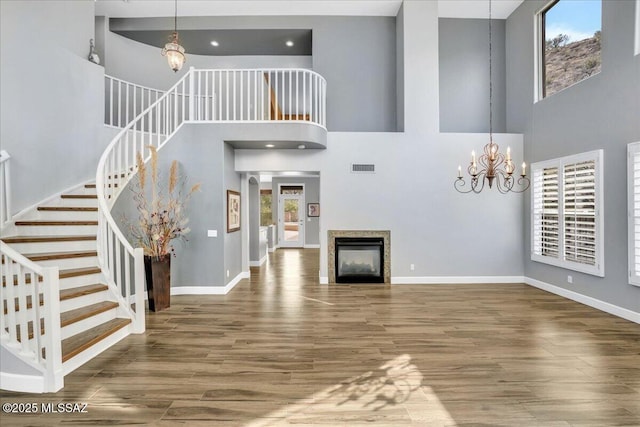 unfurnished living room featuring stairway, wood finished floors, visible vents, and a chandelier