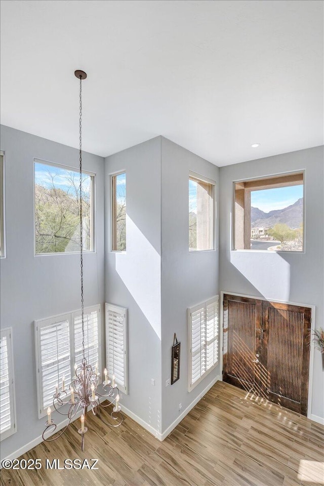 unfurnished living room with baseboards, an inviting chandelier, and wood finished floors