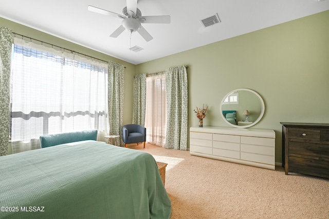 carpeted bedroom featuring visible vents, multiple windows, and a ceiling fan