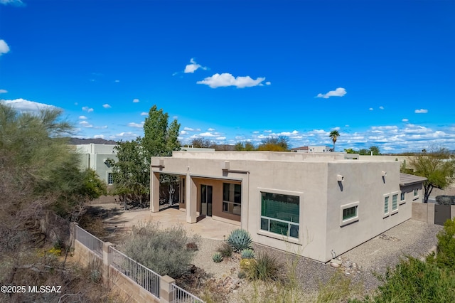 rear view of property with a patio area, fence, and stucco siding