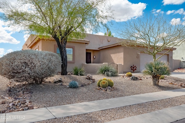 pueblo-style home featuring fence, a garage, and stucco siding