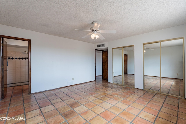 unfurnished bedroom featuring visible vents, light tile patterned flooring, multiple closets, a textured ceiling, and baseboard heating