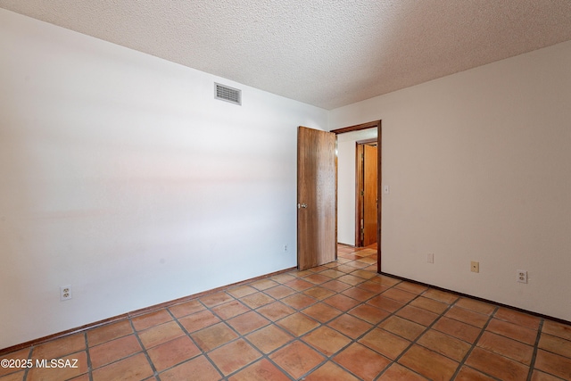 unfurnished room featuring light tile patterned floors, visible vents, and a textured ceiling