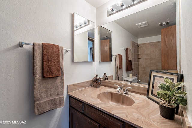 bathroom with visible vents, toilet, vanity, and walk in shower