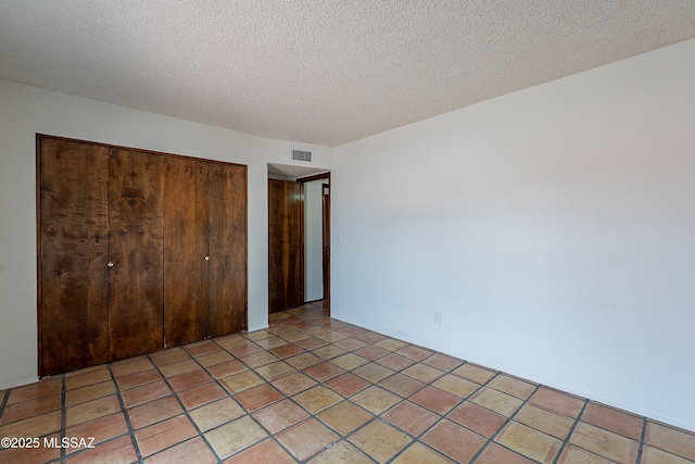 unfurnished bedroom featuring light tile patterned floors, visible vents, a closet, and a textured ceiling