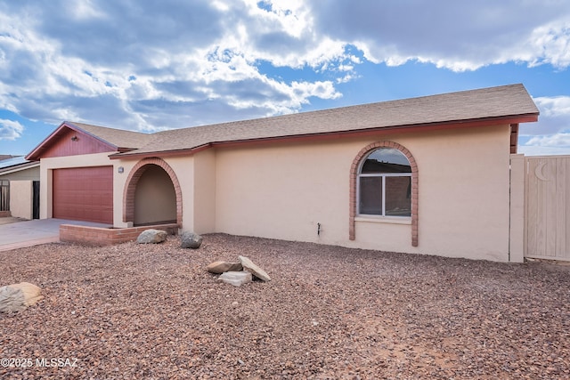 view of front of house with stucco siding, concrete driveway, a garage, and fence