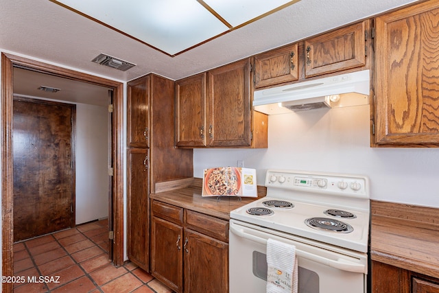 kitchen featuring light tile patterned floors, electric stove, brown cabinetry, and under cabinet range hood