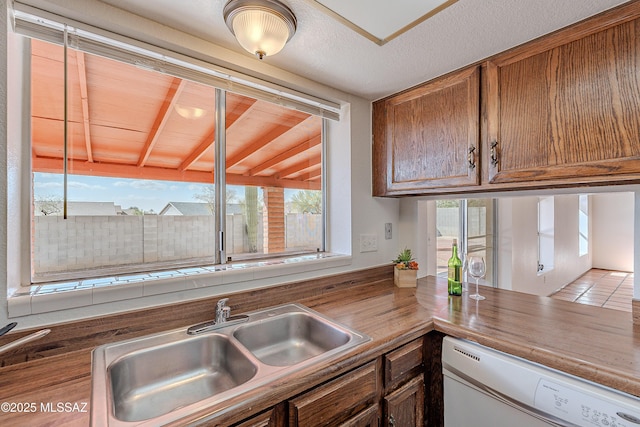 kitchen featuring a sink, brown cabinets, dishwasher, and a healthy amount of sunlight