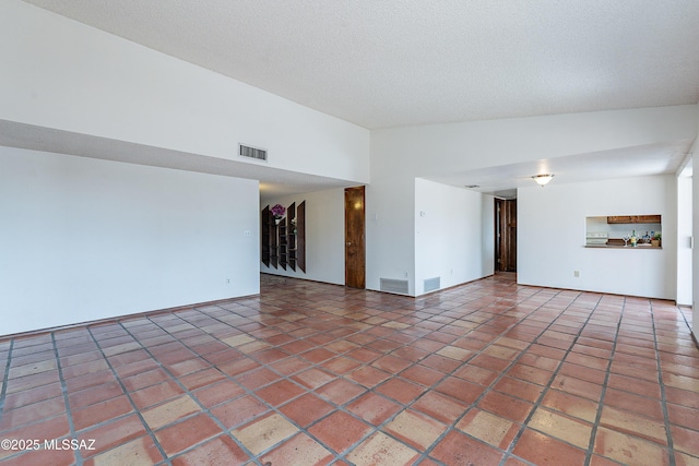 unfurnished living room featuring visible vents, lofted ceiling, a textured ceiling, and tile patterned flooring