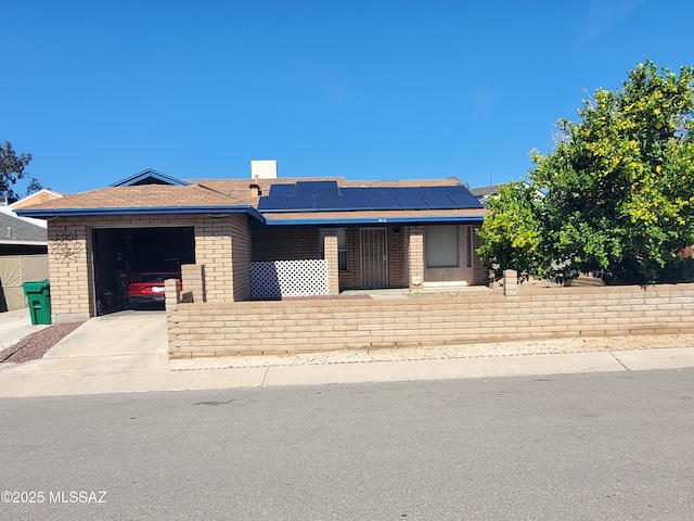 view of front of house with solar panels, an attached garage, brick siding, and driveway