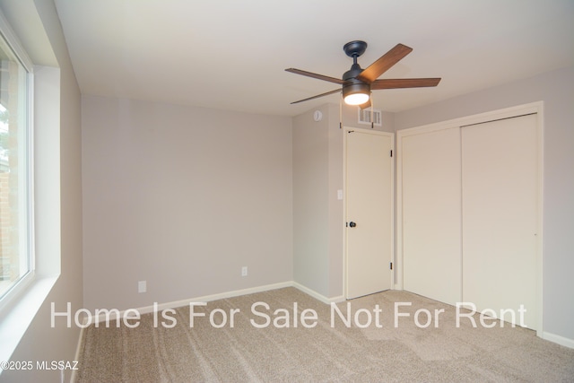 unfurnished bedroom with a closet, multiple windows, visible vents, and carpet floors