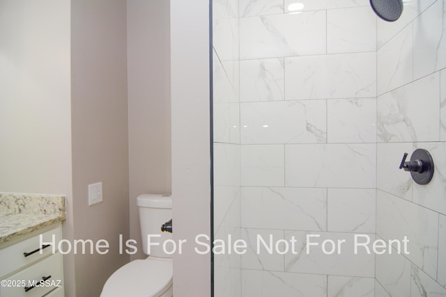 bathroom with tiled shower, toilet, and vanity