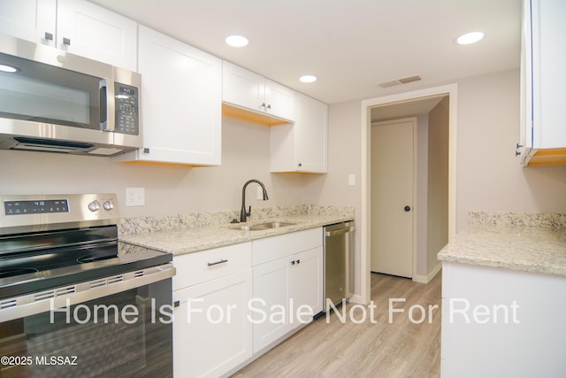 kitchen featuring visible vents, a sink, light wood-style floors, appliances with stainless steel finishes, and white cabinets