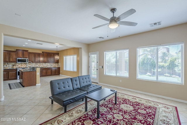 living room featuring light tile patterned floors, baseboards, ceiling fan, and visible vents