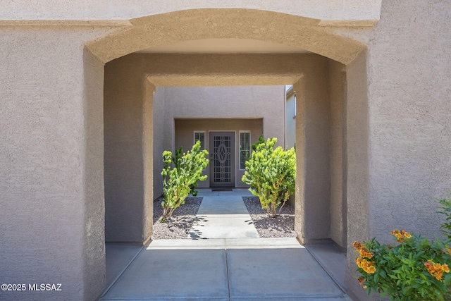 view of exterior entry with a patio area and stucco siding