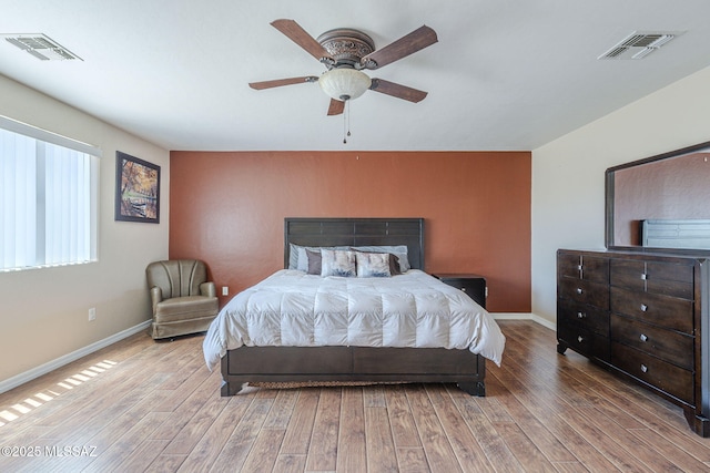 bedroom with baseboards, visible vents, and wood finished floors