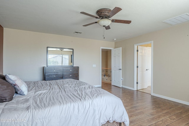 bedroom with baseboards, visible vents, and wood finished floors