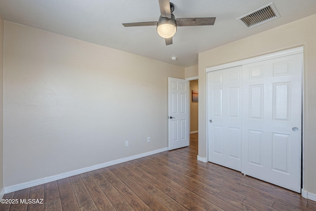 unfurnished bedroom featuring a ceiling fan, visible vents, wood finished floors, baseboards, and a closet