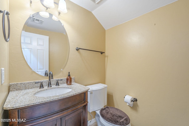 bathroom featuring toilet, visible vents, lofted ceiling, and vanity