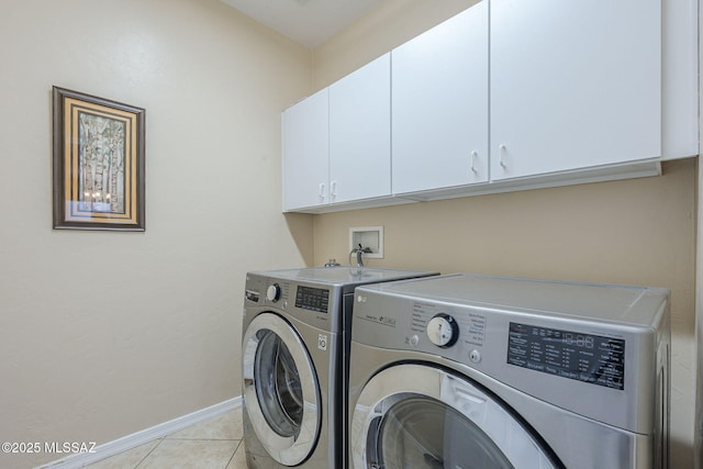 washroom with baseboards, washing machine and dryer, cabinet space, and light tile patterned flooring