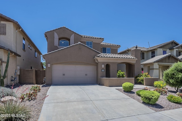 mediterranean / spanish home featuring a garage, stucco siding, a tiled roof, and concrete driveway