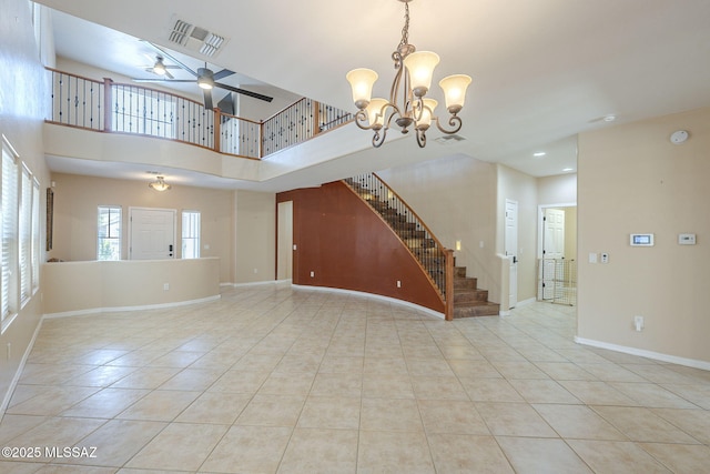unfurnished living room featuring visible vents, baseboards, stairway, tile patterned floors, and ceiling fan with notable chandelier