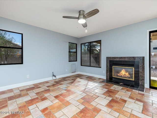 unfurnished living room featuring ceiling fan, a fireplace, and baseboards