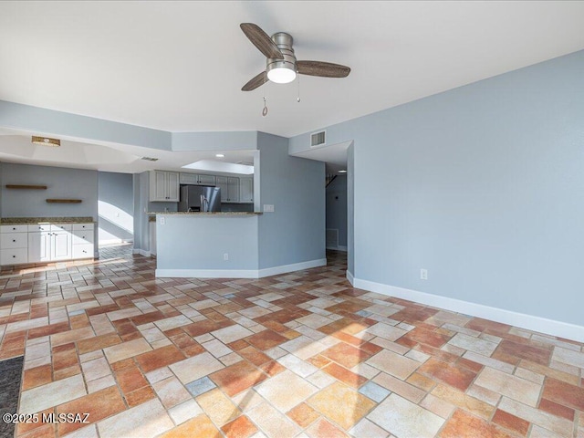 unfurnished living room featuring visible vents, baseboards, and ceiling fan