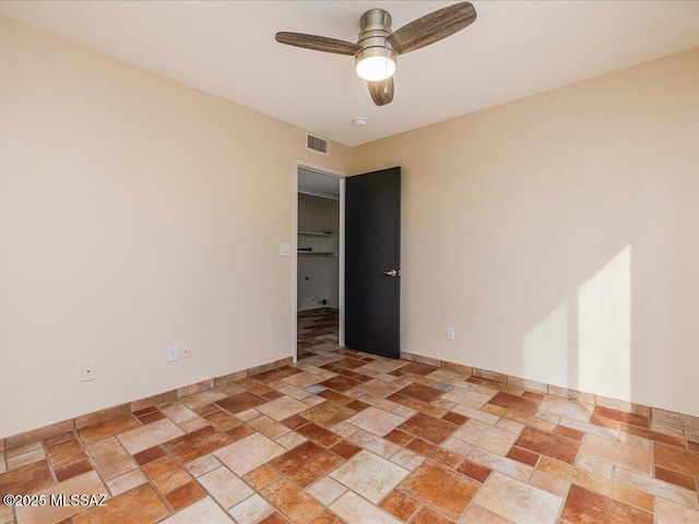 empty room featuring visible vents, baseboards, stone tile flooring, and a ceiling fan