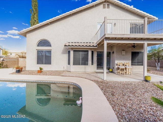 rear view of property with stucco siding, a ceiling fan, a tile roof, a patio, and a balcony