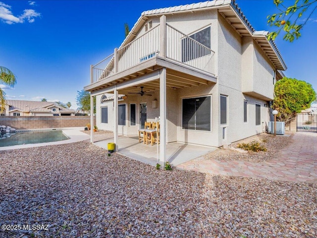 back of property with a patio, a balcony, a ceiling fan, fence, and stucco siding