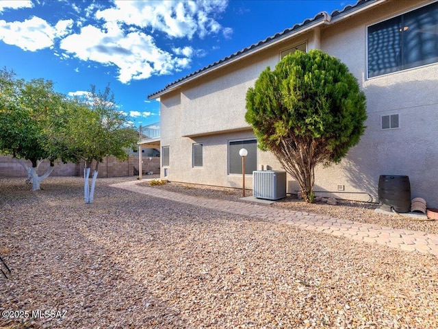 exterior space featuring a tile roof, central AC unit, and stucco siding