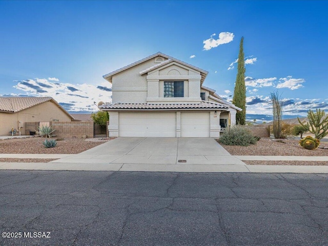 traditional-style home featuring stucco siding, driveway, a tile roof, fence, and a garage