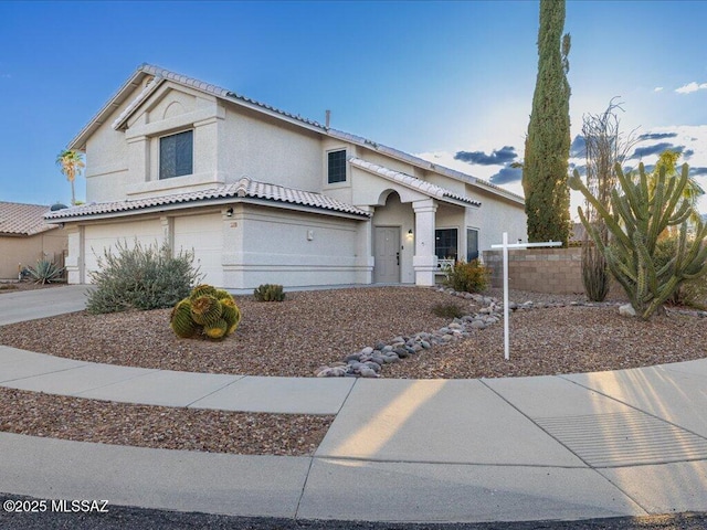 view of front of home featuring concrete driveway, an attached garage, fence, and stucco siding