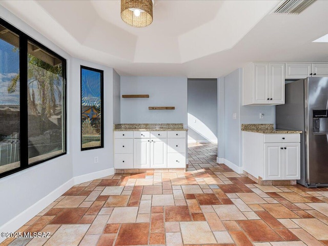 kitchen with visible vents, baseboards, a tray ceiling, stainless steel fridge with ice dispenser, and white cabinetry