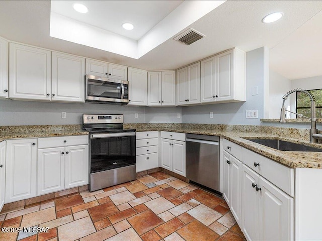 kitchen with visible vents, white cabinets, stainless steel appliances, and a sink