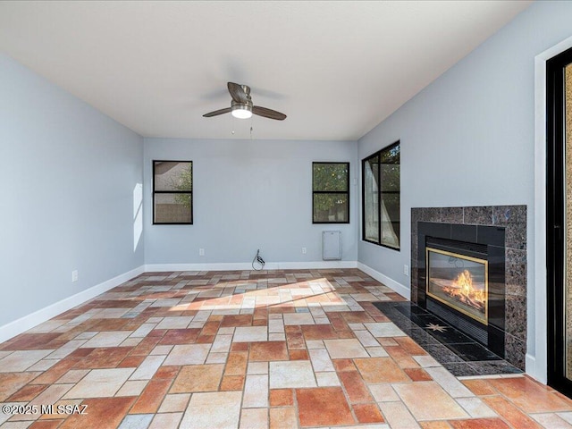 unfurnished living room featuring a fireplace, a ceiling fan, and baseboards