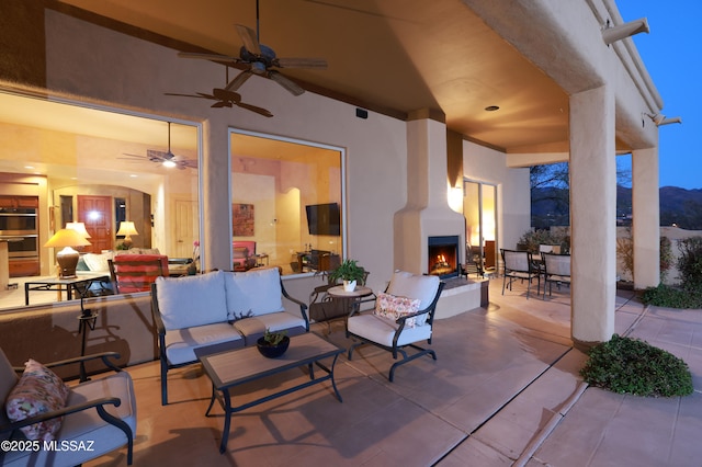 view of patio featuring an outdoor living space with a fireplace and a ceiling fan