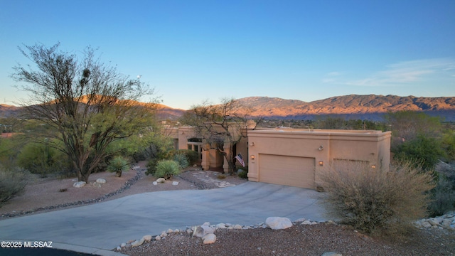 adobe home featuring concrete driveway, a garage, a mountain view, and stucco siding