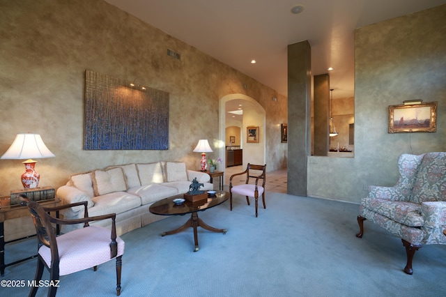 living area featuring carpet, visible vents, recessed lighting, arched walkways, and a towering ceiling