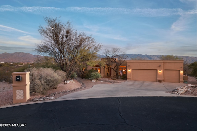 adobe home with stucco siding, a mountain view, an attached garage, and concrete driveway