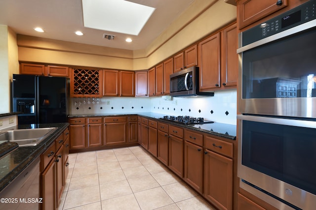 kitchen with stainless steel appliances, brown cabinets, backsplash, and visible vents