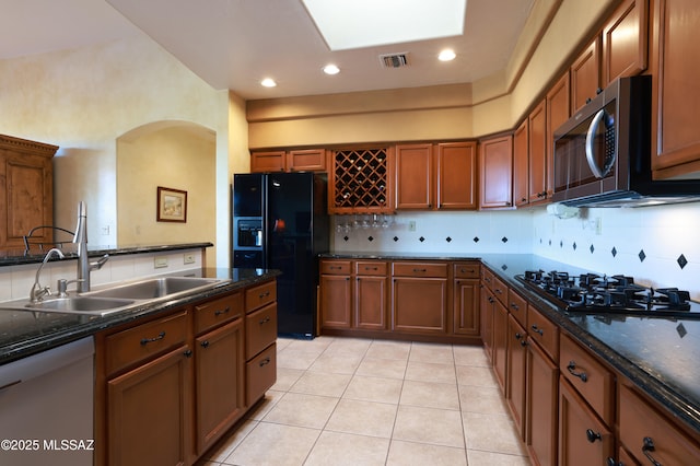 kitchen featuring black appliances, dark countertops, visible vents, and a sink