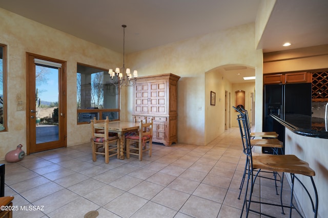 dining area featuring an inviting chandelier, light tile patterned floors, recessed lighting, and arched walkways