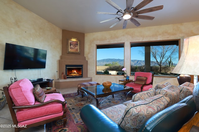 tiled living area featuring a fireplace, a ceiling fan, and a mountain view