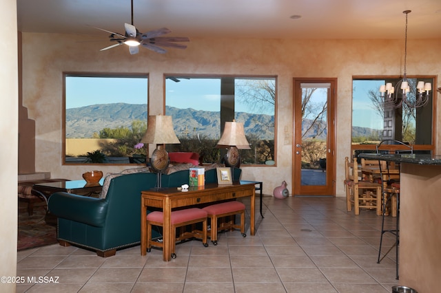 tiled living room with ceiling fan with notable chandelier and a mountain view